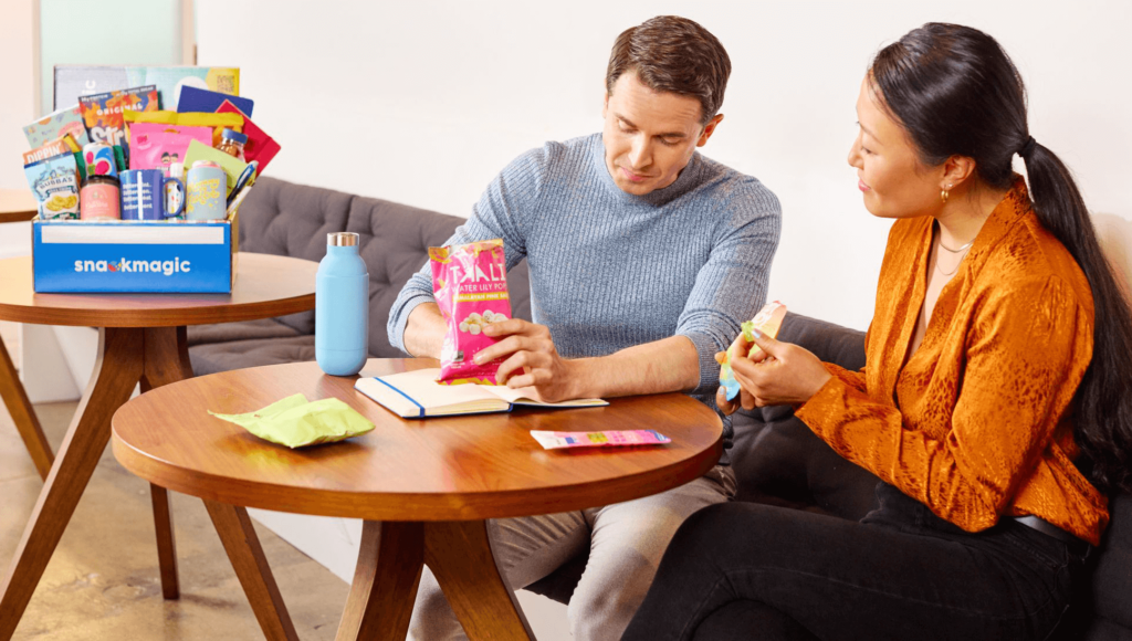 Two coworkers enjoying snacks during a productive work session.