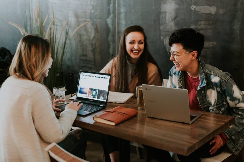 Three young professionals laughing together during a work session.