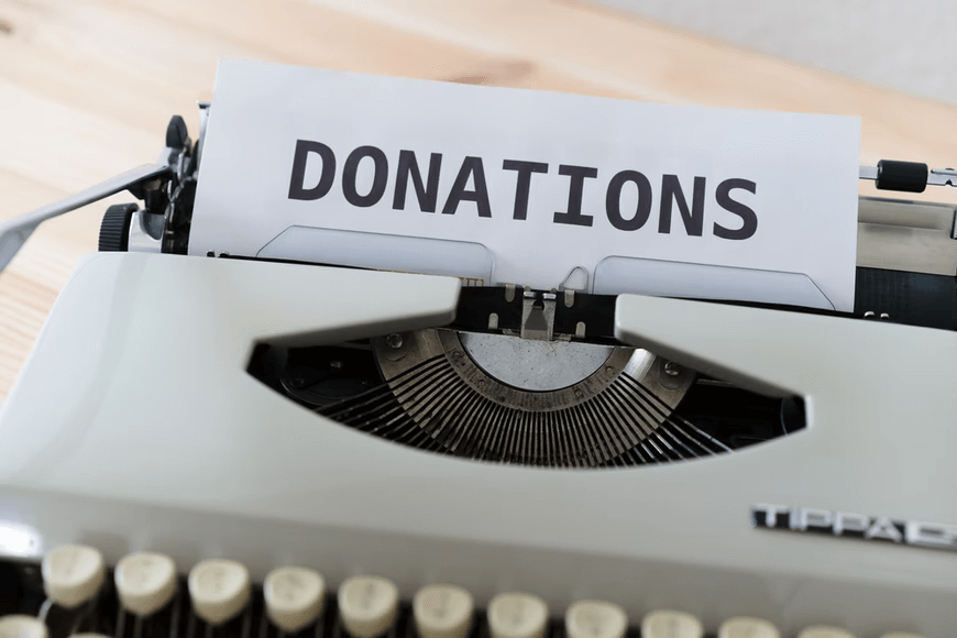 The word "DONATIONS" is typed out on a typewriter.