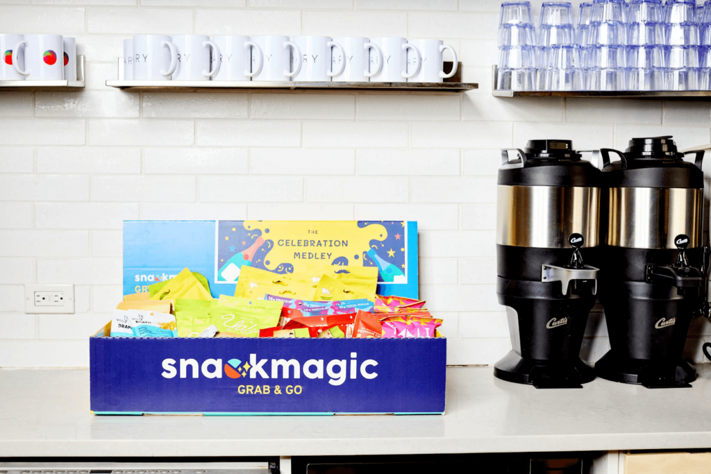 A large SnackMagic box sitting on an office's kitchen counter with coffee nearby.
