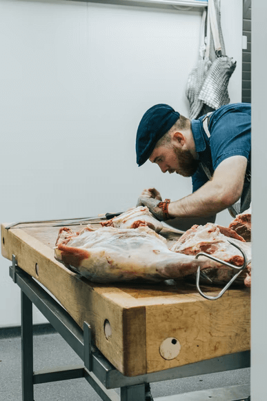 A skilled butcher carefully carving meat to make biltong. 