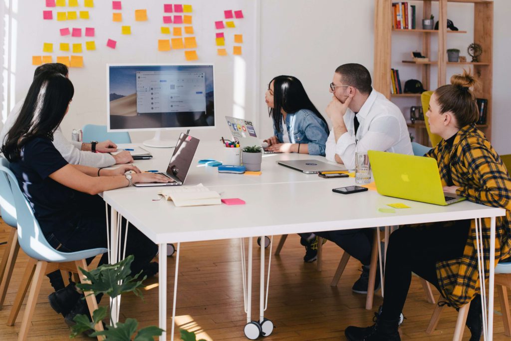 A group of employees having a meeting at a conference room table in a clean, modern office.