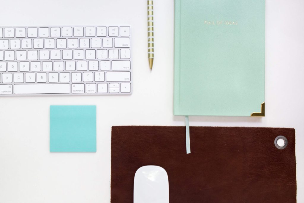 A clean assortment of brand new office supplies, like a keyboard, mouse, and notebook.l