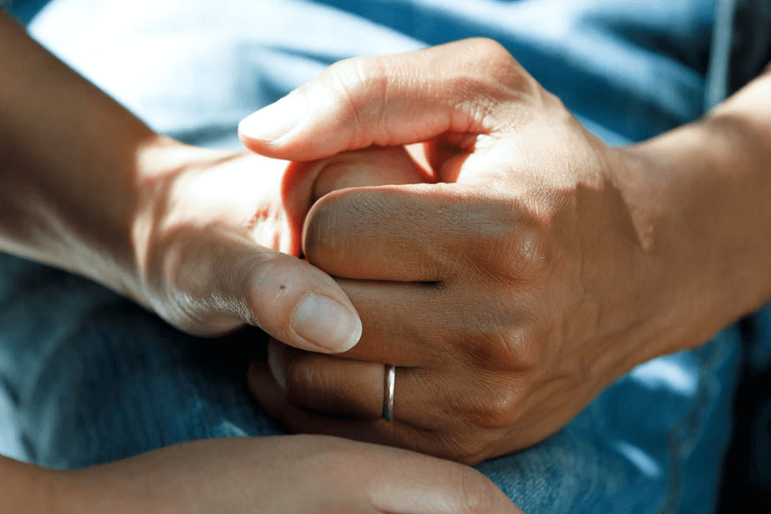 Two people's clasped hands, a gesture and a picture of support.