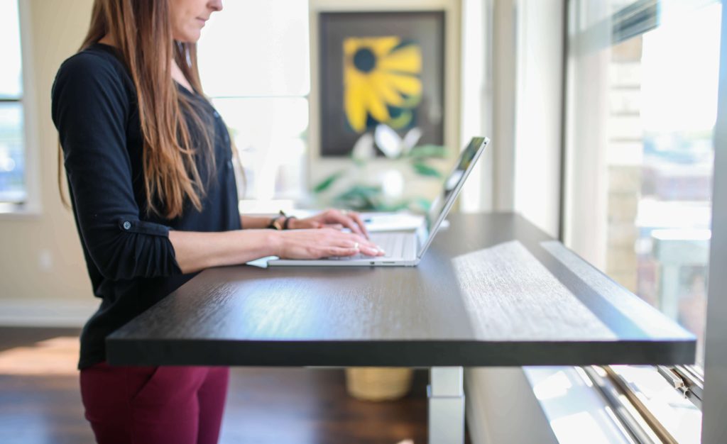 A remote employee works at a standing desk in her home office. 