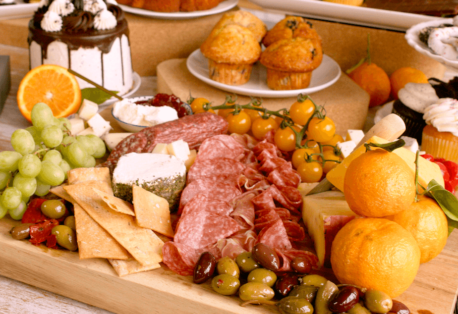 A generous helping of meats, cheeses, fruits, olives and more presented on a charcuterie board.