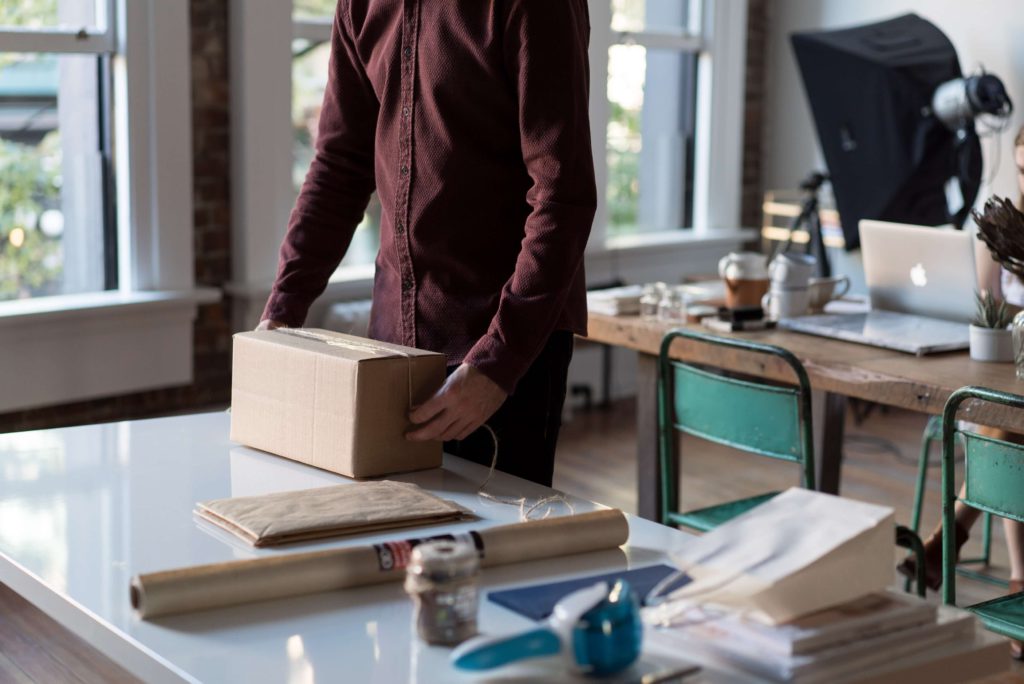 An employee in a shared office wrapping a gift for a client.