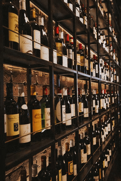 A large selection of wine, displayed on rows of shelves in a store.