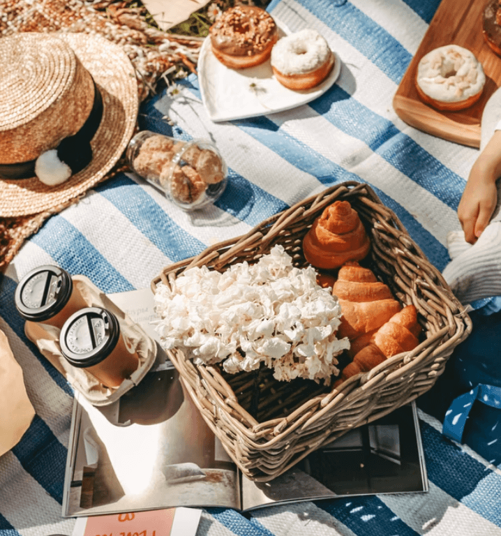 An appealing outdoor picnic spread full of coffees, fresh flowers, snacks and more.