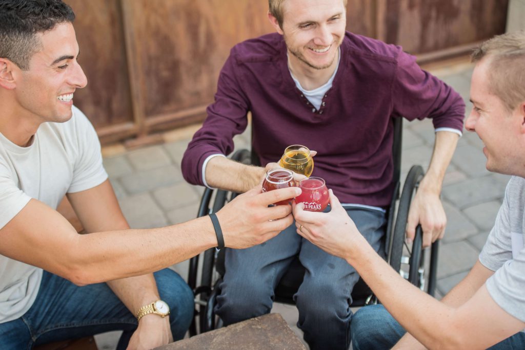 Three young men enjoying a drink together, posing for a cheers picture 