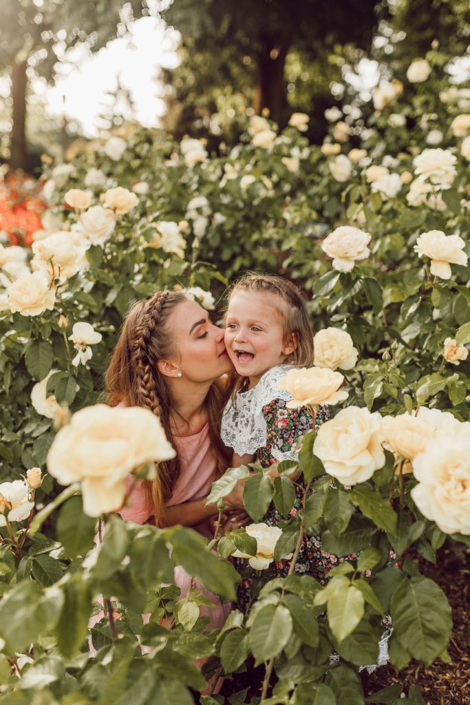 A mother and a daughter sharing a nice moment outside among flowers.