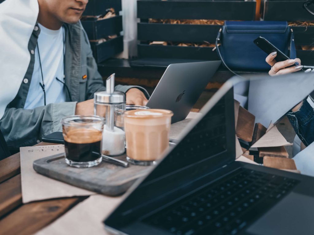 A coworking space with open laptops and chatting teammates, enjoying lattes and coffees.  